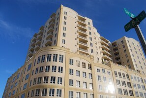 Um edifício residencial com vários andares, varandas, janelas amplas e céu claro.