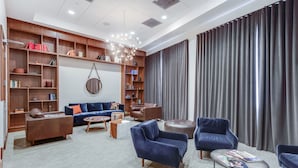 Una sala de estar moderna con un sofá, sillones, una mesa de centro y una estantería.