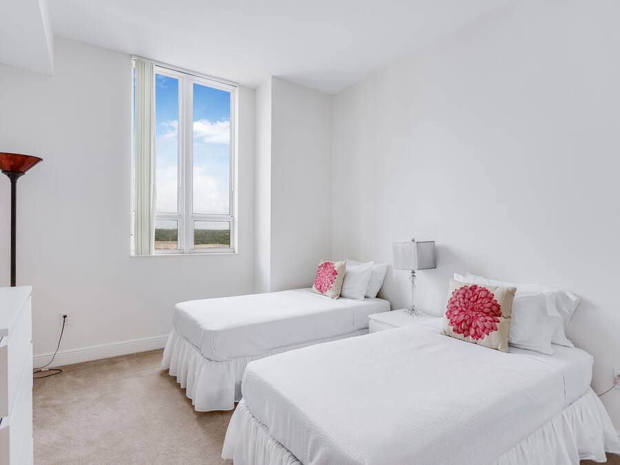 Un dormitorio con dos camas, una ventana, una lámpara y un escritorio.
