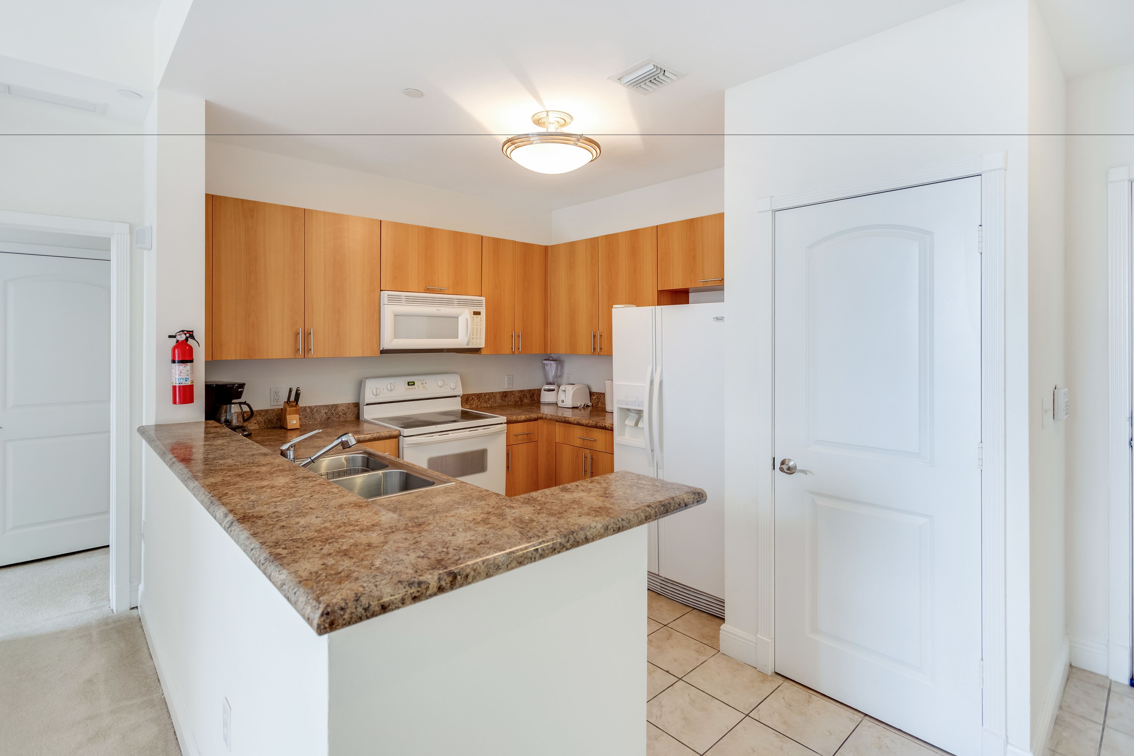 Una cocina moderna con encimeras de granito, armarios de madera, un microondas, una estufa y un refrigerador.
