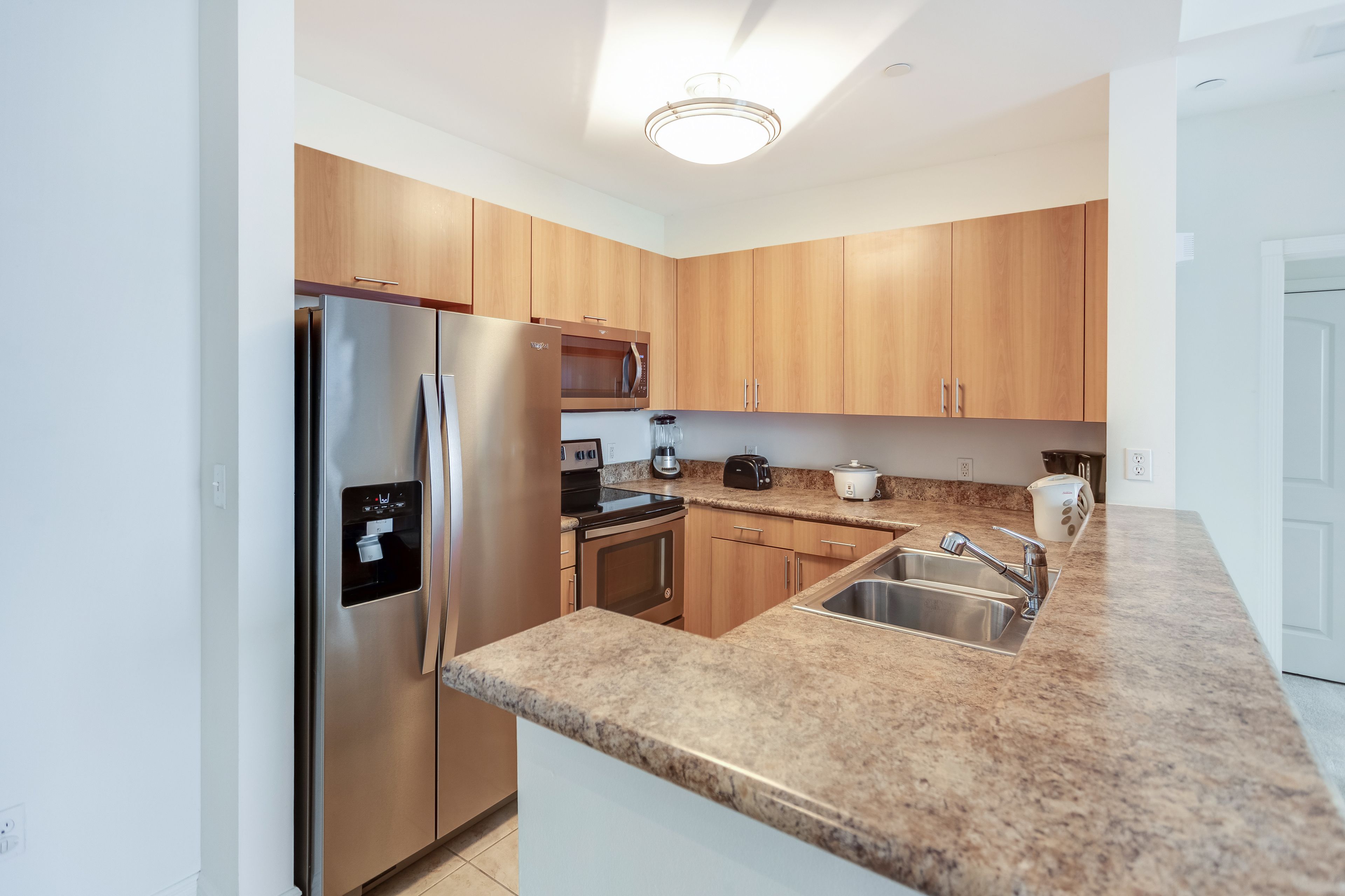 A modern kitchen with wooden cabinets, stainless steel appliances, granite countertops, and a built-in oven.