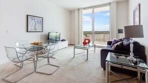 Una sala de estar moderna con una mesa de comedor de vidrio, un sofá y un ventanal con vistas al exterior.
