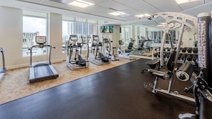 Un gimnasio con cintas de correr, elípticas y equipo de pesas.