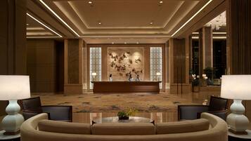 A spacious lobby with a reception desk, a large decorative wall, and a polished floor.