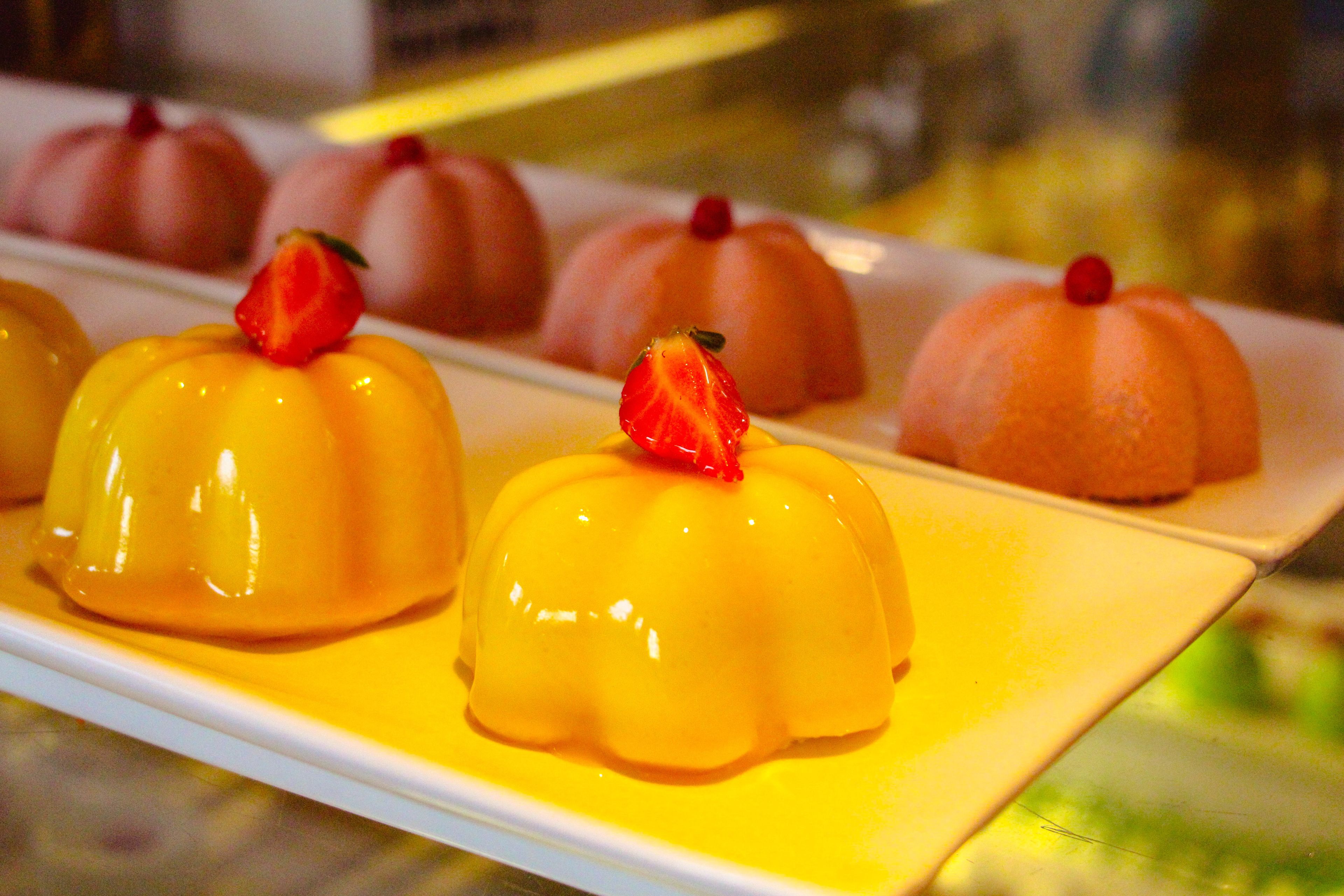 A dessert display with various shaped sweets topped with strawberries.