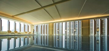 Una piscina techada, sillones reclinables de piscina