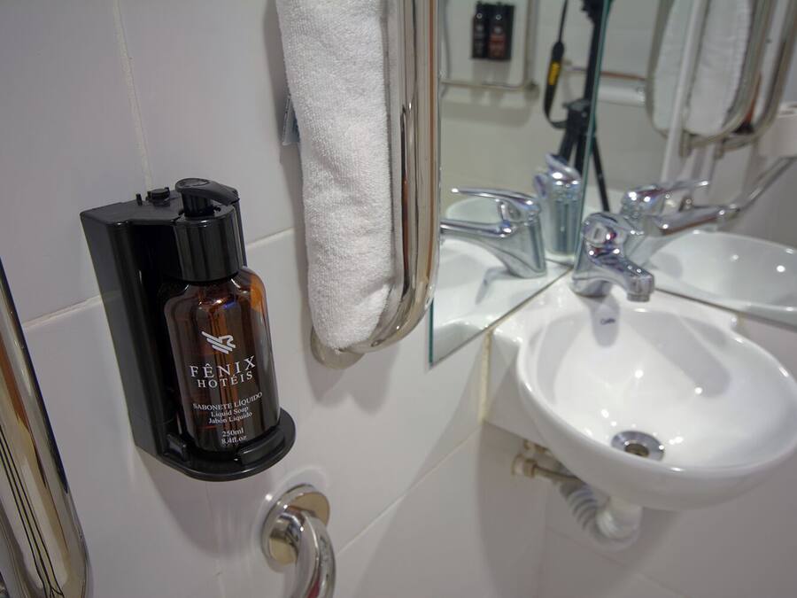 A bathroom with a white sink, a mirror, and a bottle of Fenix lotion.
