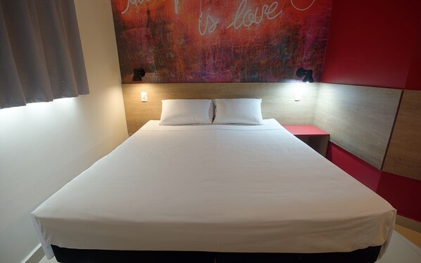 A neatly made bed with white linens in a room with a red accent wall and a motivational quote. - Golden Tower Express Franca by Fênix Hotéis (Franca)