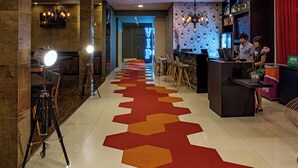 Un hall d’hôtel au design moderne, comprenant un comptoir d’accueil, un espace salon et un tapis décoratif.