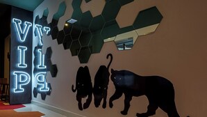 Un intérieur moderne agrémenté d’un néon affichant le mot « VIP », d’un mur orné de miroirs hexagonaux et d’une silhouette de panthère.