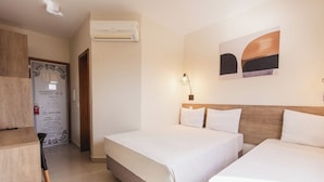 Ein Hotelzimmer mit einem Bett, einem Schreibtisch und einem Stuhl. An der Wand ist eine Klimaanlage angebracht und ein gerahmtes Zertifikat hängt dort.