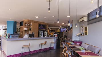 Zona de bar moderna con barra, taburetes y diferentes disposiciones de asientos.
