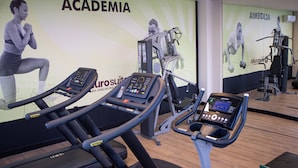 Ein Fitnessraum mit Laufbändern, einem Ergometer und einer Wand mit Fitnesspostern.