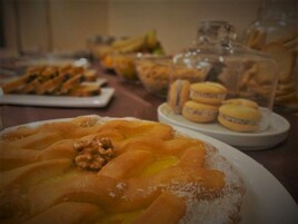 Uma mesa de sobremesas com diversos doces e um prato de fatias de maçã cobertas com nozes.