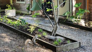 A garden with a wooden house, a tree, and a person tending to plants. - The Trail in Adams - Berkshires’ Art Hotel (Adams)