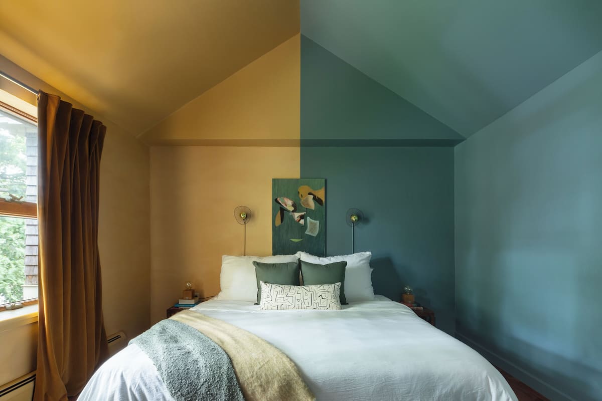 A bedroom with a bed, a nightstand, a lamp, and a window with curtains.