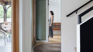 A hallway with a wooden door, a bench, and a staircase. - The Trail in Adams - Berkshires’ Art Hotel (Adams)