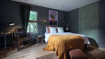 A bedroom with a bed, a desk, a chair, a window, and a painting on the wall.