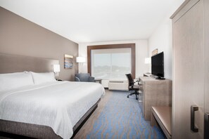 A hotel room with a large bed, a desk with a computer, a chair, a television, and a window with a city view. - Holiday Inn Express & Suites Great Bend by IHG (Great Bend)