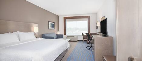 Une chambre d’hôtel avec un grand lit, un bureau avec une chaise, une télévision et une fenêtre donnant sur un beau paysage.