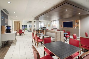 A modern cafe with multiple seating areas, including booths and tables, and a coffee machine on the counter.