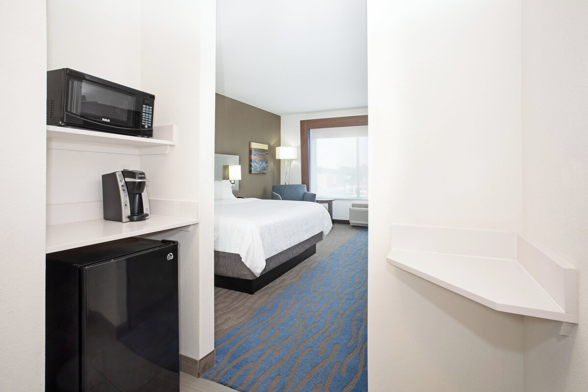 Habitación de hotel con cama, microondas, cafetera y ventana.