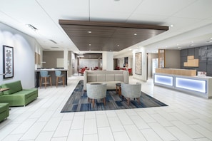 A modern hotel lobby with a reception desk, seating area, and a large sofa. - Holiday Inn Express & Suites Great Bend by IHG (Great Bend)