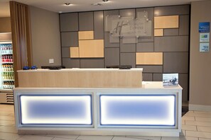 A hotel reception desk with a modern design, a water cooler, and a sign indicating check-in times. - Holiday Inn Express & Suites Great Bend by IHG (Great Bend)
