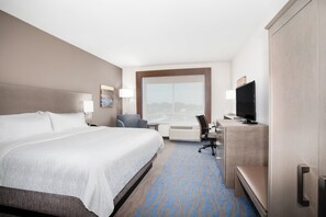 A hotel room with a large bed, a desk with a computer, a TV, and a window with a city view. - Holiday Inn Express & Suites Great Bend by IHG (Great Bend)