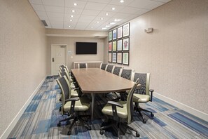 A conference room with a long table, chairs, a flat-screen TV, and patterned wall decorations. - Holiday Inn Express & Suites Great Bend by IHG (Great Bend)