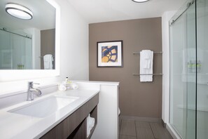 Un baño moderno con un espejo grande, un lavabo blanco y una cabina de ducha de cristal.