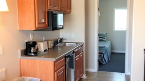 A compact kitchen with wooden cabinets, a microwave, a coffee maker, and a dishwasher. - Village Marina (Hatteras)