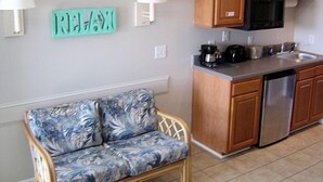 A compact kitchen with wooden cabinets, a built-in microwave, and a stainless steel dishwasher. - Village Marina (Hatteras)