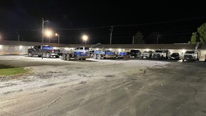 A parking lot at night with several trucks and a trailer. - Budget Inn (Ada)