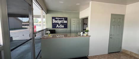 Una recepción con un cartel que dice 'Welcome to the Budget Inn of Ada'.