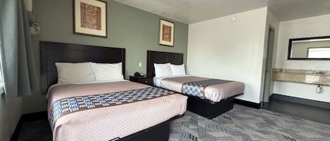 A hotel room with two beds, a nightstand, a mirror, and a wall-mounted light fixture.