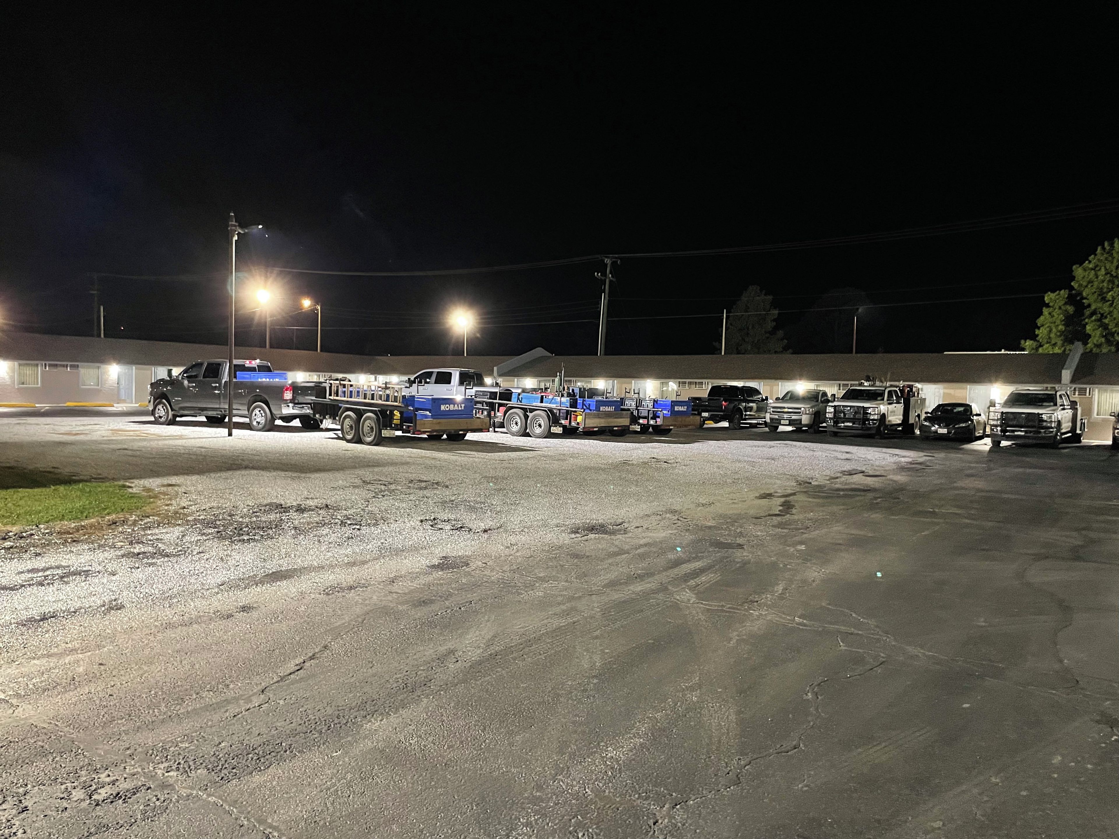 A parking lot with several trucks and a building in the background.