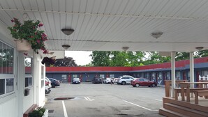 A motel with a covered parking area, multiple rooms, and a small outdoor seating area. - Niagara Inn & Suites (Niagara Falls)