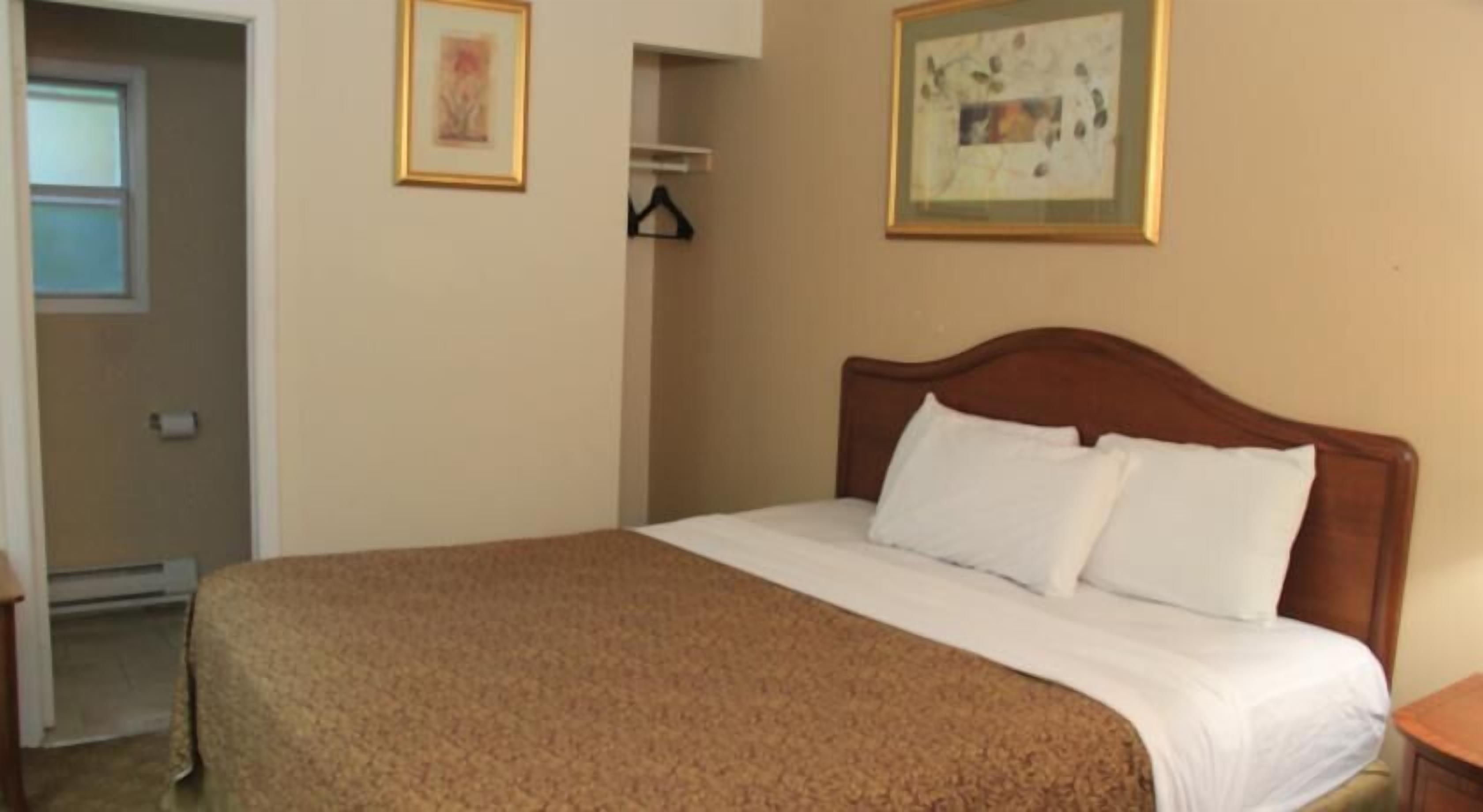Une chambre à coucher avec un lit, une tête de lit en bois et deux tableaux encadrés accrochés au mur.