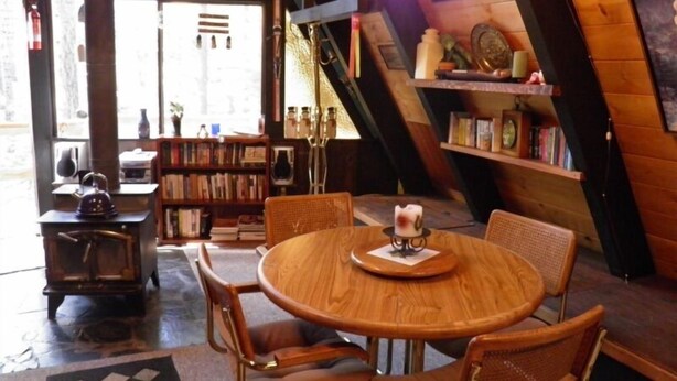 A cozy room with a wooden table and chairs, a bookshelf, and a small stove. - 916 Kiowa (South Lake Tahoe)