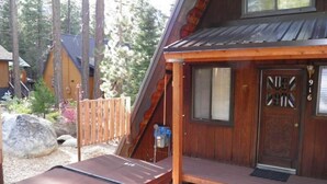 A wooden cabin with a porch, a hot tub, and a wooden deck. - 916 Kiowa (South Lake Tahoe)