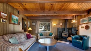 A cozy living room with a sofa, armchairs, a coffee table, and a fireplace. - 890 Candlewood Drive (South Lake Tahoe)