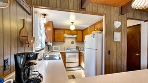 A kitchen with wooden cabinets, a white refrigerator, a stove, and a coffee maker. - 890 Candlewood Drive (South Lake Tahoe)
