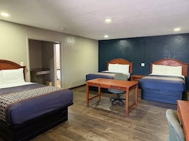 Habitación de hotel con dos camas, un escritorio y una silla.