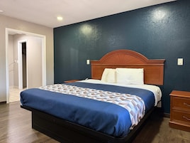 Una habitación de hotel con una cama, cabecera de madera y una mesita de noche.