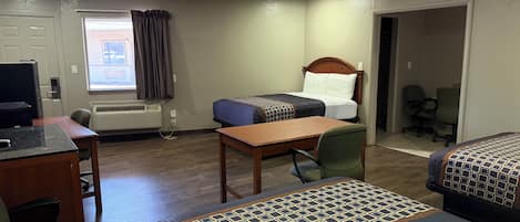 A hotel room with two beds, a desk, a chair, a television, and a window with curtains.