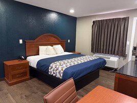 Quarto de hotel com cama, mesa de cabeceira, cadeira e ar condicionado.