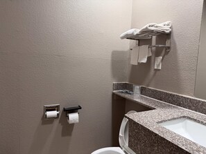Une salle de bain dotée d’un comptoir en granit, de toilettes et d’un porte-serviettes avec des serviettes.
