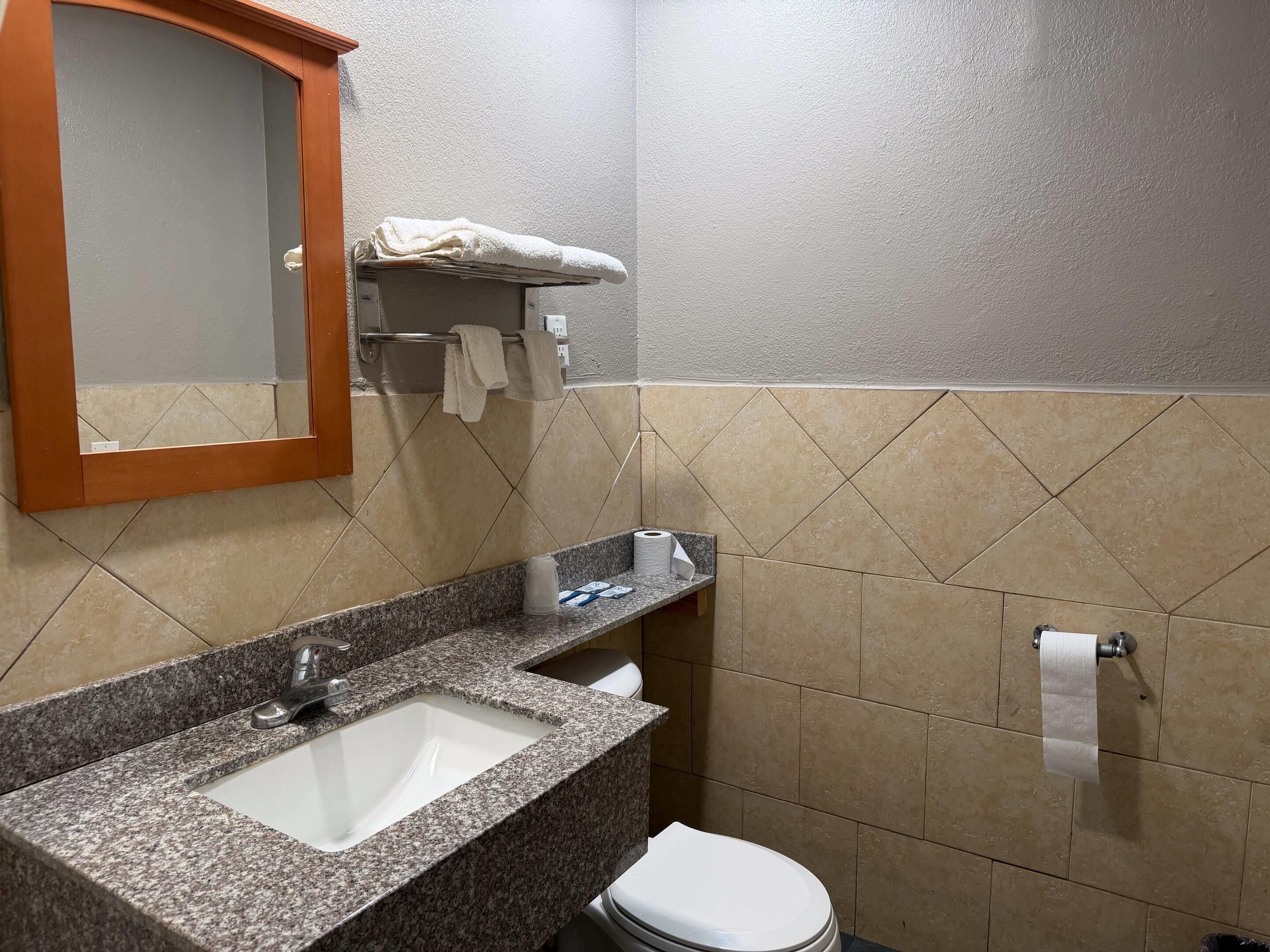 A bathroom with a granite sink, a toilet, and a towel rack.