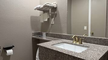 Un baño con lavamanos de encimera de granito, grifo dorado, toallero y un inodoro.